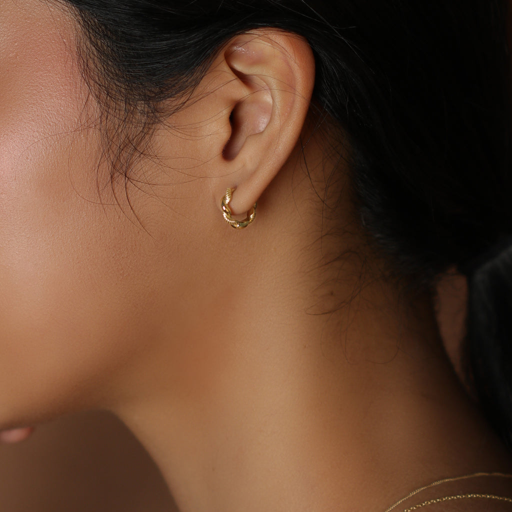 Aurora Twist Small Hoops 18k gold stacked on model ear – Foundry