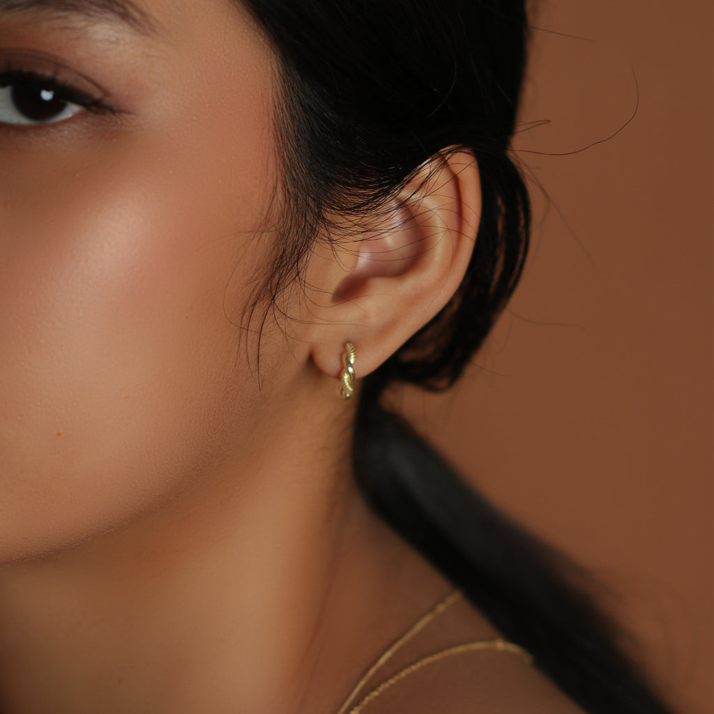 Aurora Twist Small Hoops 18k gold stacked on model ear – Foundry