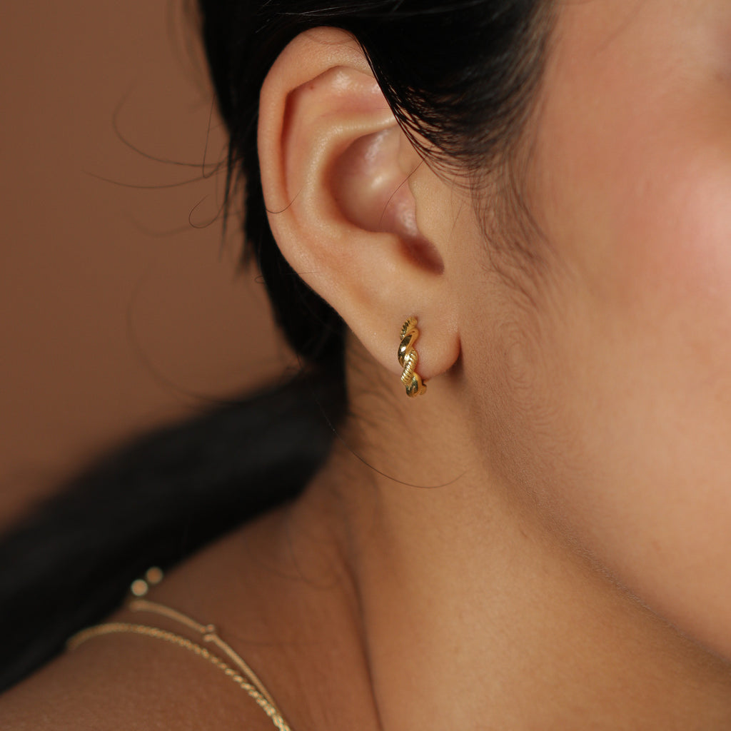 Aurora Twist Small Hoops 18k gold stacked on model ear – Foundry