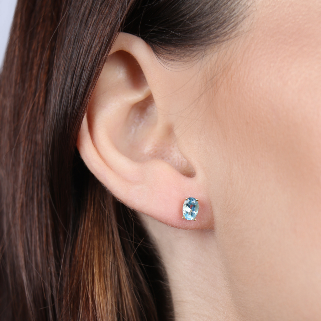Birthstone Oval Studs Blue Topaz 18k gold stacked on model ear – Foundry
