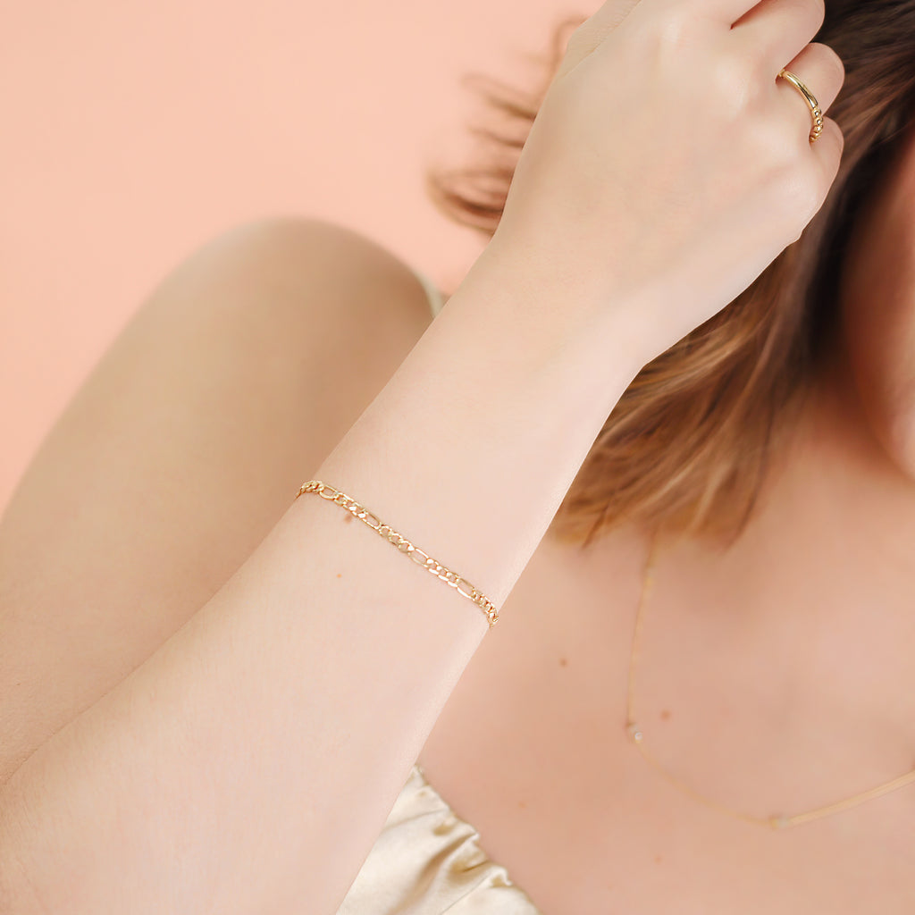 Figaro Chain Bracelet 14k gold stacked on model wrist – Foundry
