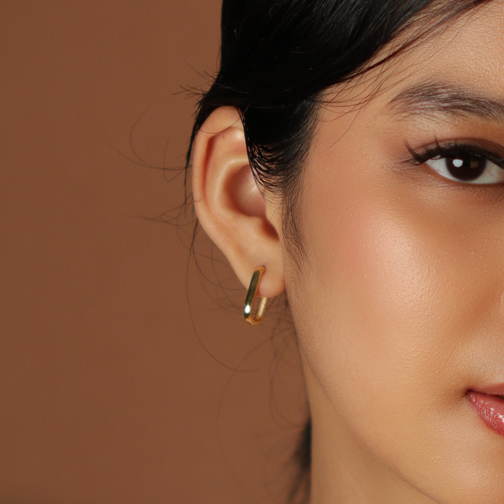 Huggie U Hoops 18k gold stacked on model ear – Foundry