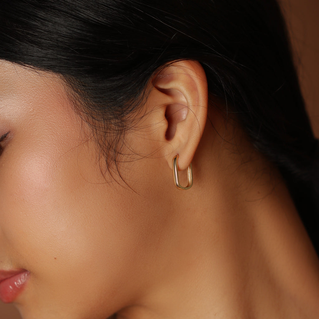 Huggie U Hoops 18k gold stacked on model ear – Foundry