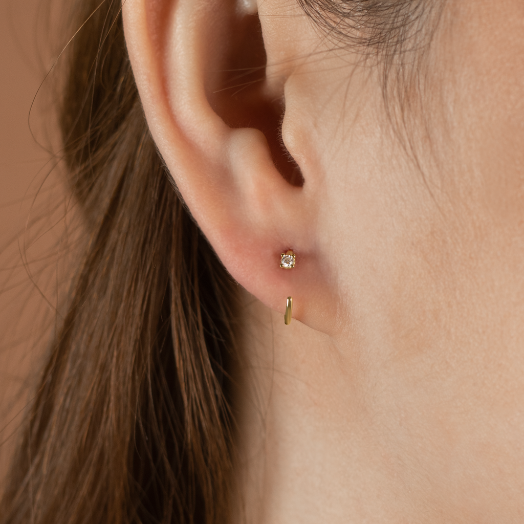 Reversible Solo Huggie Hoops 14k gold stacked on model ear – Foundry