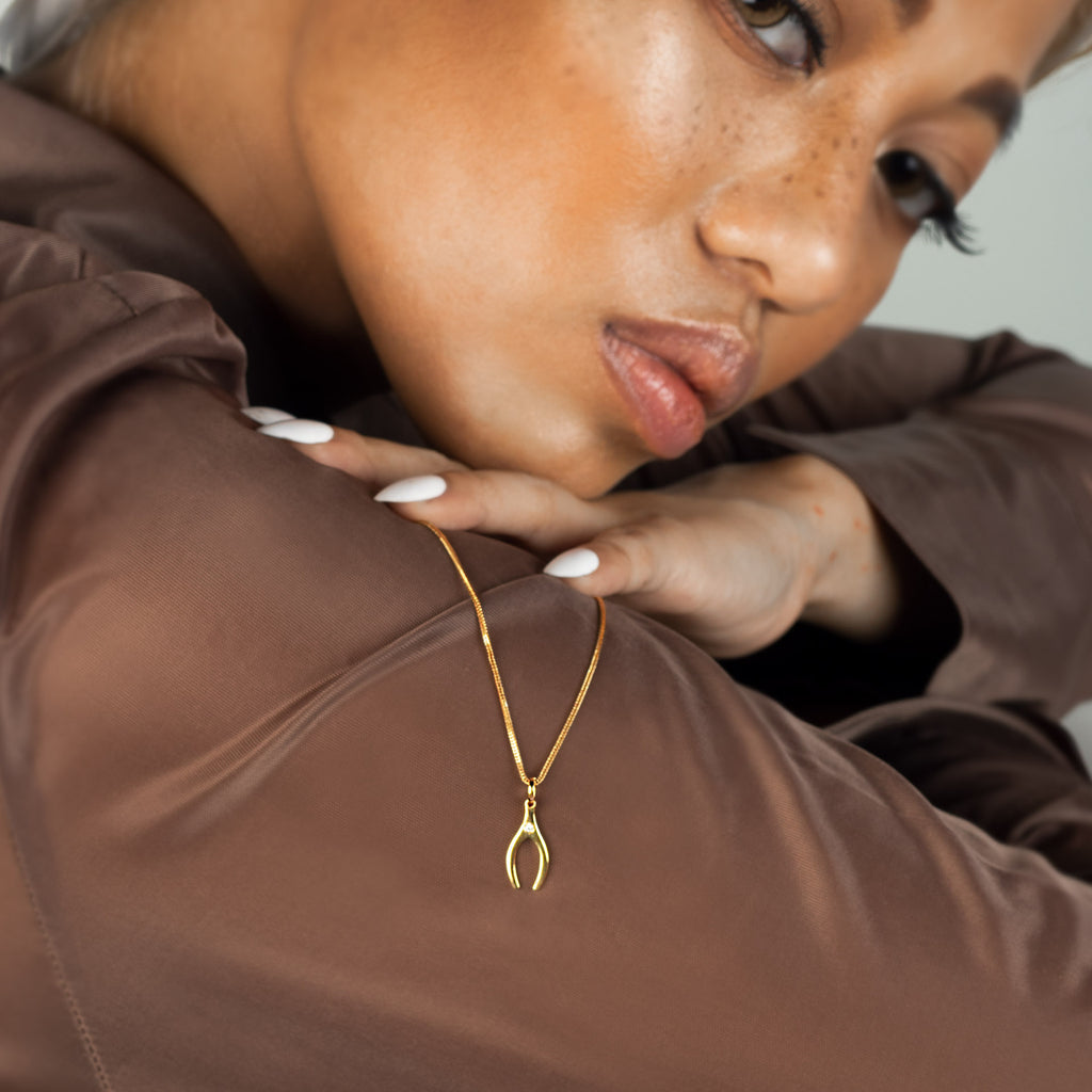 Wishbone Charm 18k gold stacked on model finger – Foundry